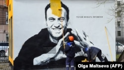 Рабочий закрашивает мурал с Навальным. 