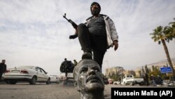 СИРИЯ – Боец оппозиции наступает на сломанный бюст покойного президента Сирии Хафеза Асада в Дамаске, Сирия, 8 декабря 2024 г.