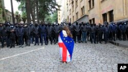 Протестираща със знамената на Грузия и ЕС пред полицейски кордон в Тбилиси, 14 май 2024 г.