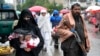 An Afghan woman walks through a market as a Taliban fighter stands guard in Kabul. (file photo)