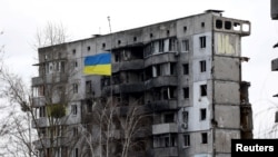 Украински национален флаг пред разрушена жилищна сграда в Бородянка на 18 февруари.