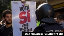Сторонник независимости Каталонии с плакатом "Проголосуй за "Да" перед испанским полицейским. Барселона, 20 сентября