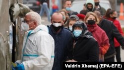 Disa njerëz duke pritur para Qendrës Klinike Universitare të Kosovës.