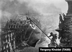 Солдат 150-ї дивізії РСЧА встановлює прапор на будівлю Рейхстагу. Берлін, Третій Рейх, 30 квітня 1945 року