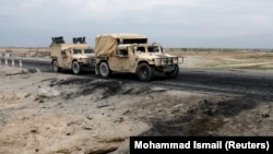 An Afghan military convoy drives past the site of a car bombing where U.S soldiers were killed near Bagram air base on April 9.