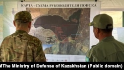 Военные смотрят на карту озера Сорбулак, в котором ведутся поиски вертолета EC-145. Алматинская область, 30 июля 2025 года
