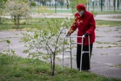 Літня жінка з ходунками біля вишні