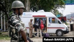 A member of India's security forces stands guard as police search a van on the Jammu-Srinagar highway at Nagrota on August 2.