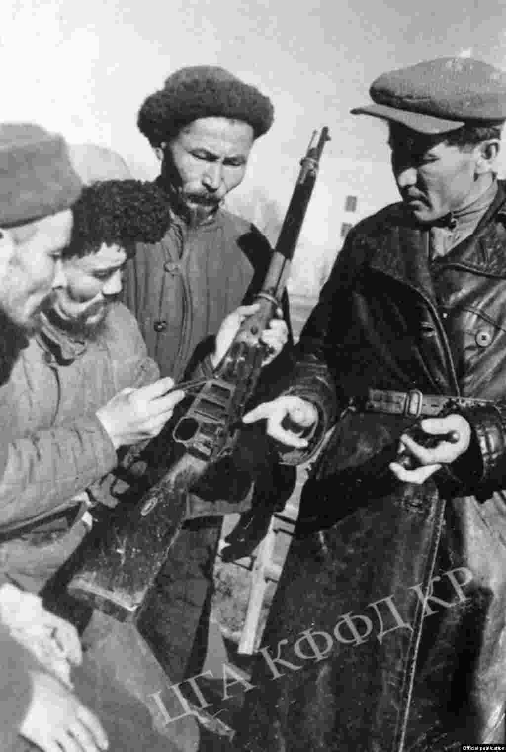Бойцы всевобуча изучают винтовку (слева на право) Умарбек Умарбаев, Эштай Джанабаев, Джумагул Керимбаев, командир взвода Ханафий Нигматулин. Город Фрунзе. Автор съемки: К.Вильчинский. 1943 год.&nbsp;
