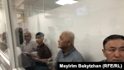 Нурлан Темиргалиев, Фазылжан Сыдыков, Айдар Мубараков, Нурлан Жауылбаев (справа налево) в стеклянной кабине в зале суда. 17 июля 2025 года
