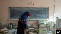 افغانستان - یک معلم کتاب‌ها را در یک مکتب در کابل جمع‌آوری می‌کند.
