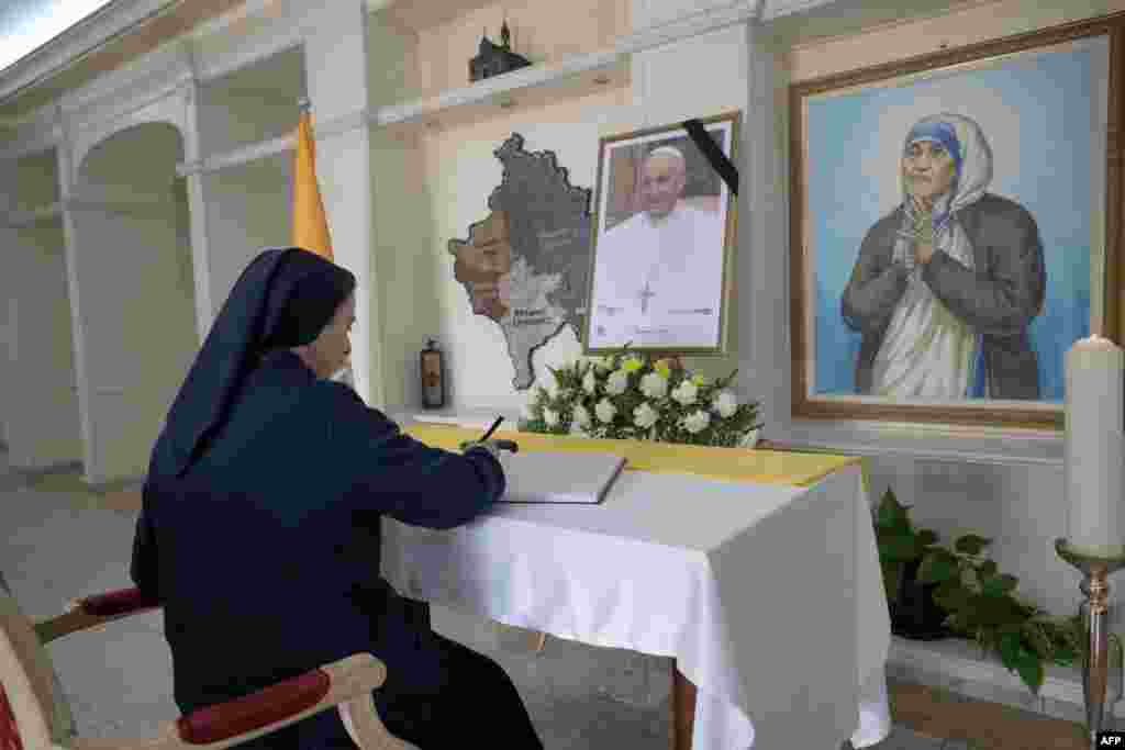 O călugăriță catolică semnează cartea de condoleanțe lângă un portret al regretatului Papă Francisc expus la Catedrala Sfânta Maica Tereza din Priștina, Kosovo. 24 aprilie 2025.