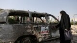 Израилдин аба соккуларынан кийин күйүп кеткен машиненин жанында турган ирандык аял. Тегеран, Иран. <br>