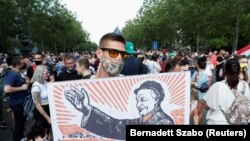 Egy tüntető Orbán Viktor miniszterelnököt Mao Ce-tungként ábrázoló plakátot visz a kínai Fudan Egyetem tervezett budapesti campusa elleni tiltakozáson 2021. június 5-én